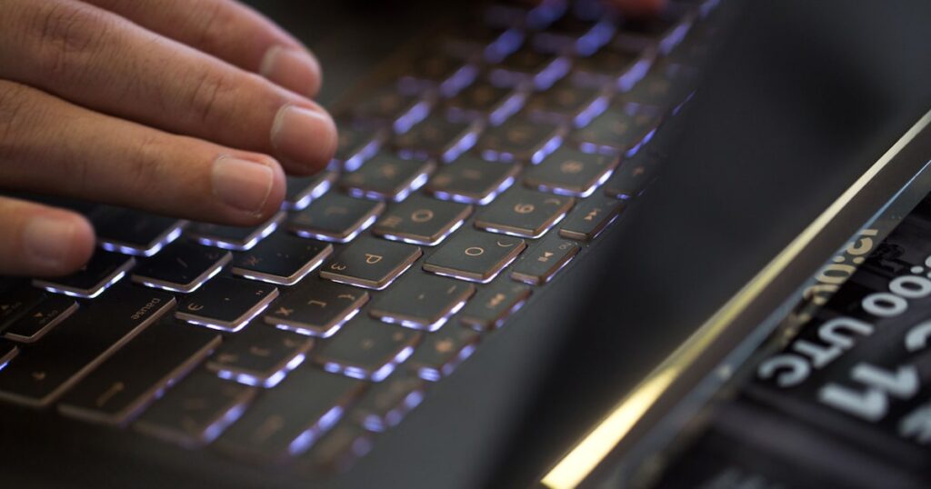 Gráfico de un hombre recibiendo un correo electrónico de phishing en su computadora, con una imagen de fondo de una ciudad de Latinoamérica
