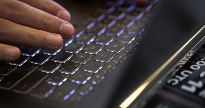 Gráfico de un hombre recibiendo un correo electrónico de phishing en su computadora, con una imagen de fondo de una ciudad de Latinoamérica