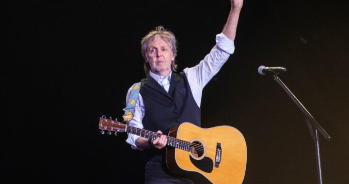 Paul McCartney sonriendo y hablando con un micrófono en mano