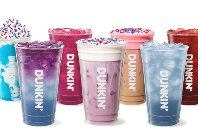 Una persona sosteniendo una taza de Dunkin' con decoraciones de águila en un vaso de vidrio tridimensional en forma de águila