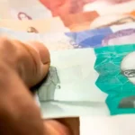 Imagen de una persona ahorrando dinero en un banco, con un gráfico de economía al fondo que muestra la absorción del ahorro por el Gobierno