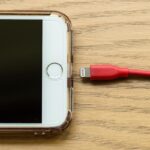 Una mano sosteniendo un celular con un cargador conectado de forma segura