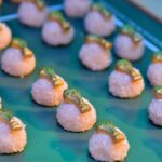 Un chef preparando un plato de degustación con ingredientes frescos como mariscos y guayaba