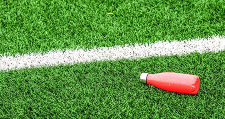Persona bebiendo agua de coco en un estadio de fútbol