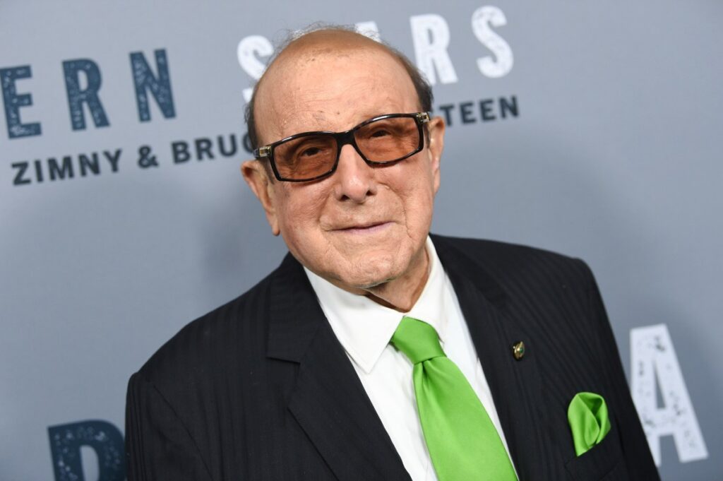 Clive Davis sonriendo en una imagen de archivo, rodeado de discos de oro y artistas famosos