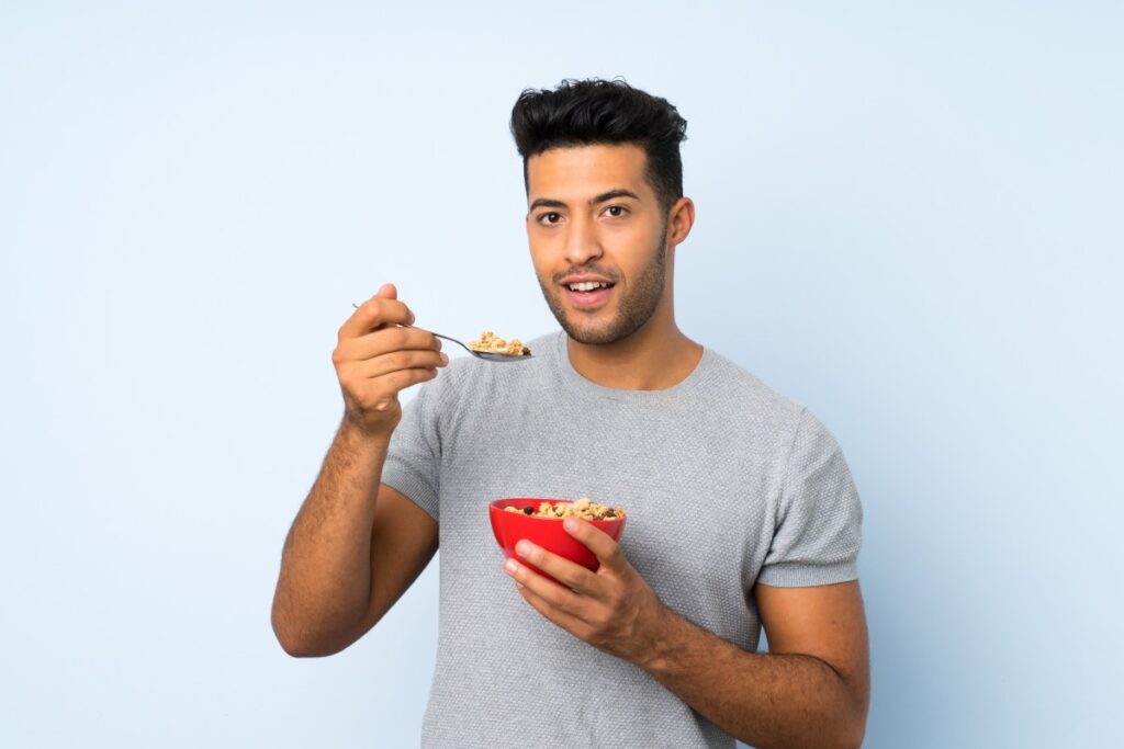 Una mujer con un rostro saludable y atractivo sonriendo mientras come alimentos frescos y naturales.