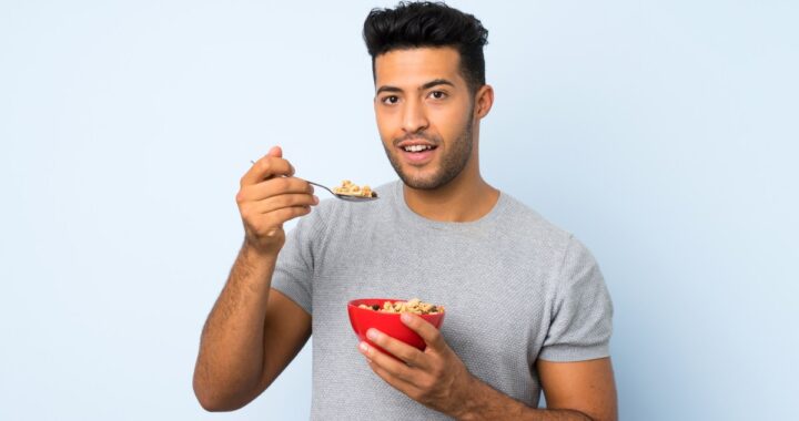Una mujer con un rostro saludable y atractivo sonriendo mientras come alimentos frescos y naturales.