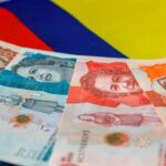 Imagen de una persona sosteniendo un billete de peso colombiano, con un gráfico de divisas al fondo.