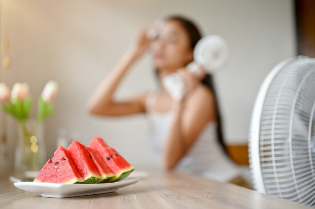 Una sandía y fresas frescas sobre una mesa de madera, rodeadas de agua y hojas verdes