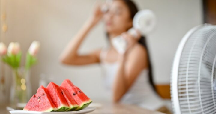 Una sandía y fresas frescas sobre una mesa de madera, rodeadas de agua y hojas verdes