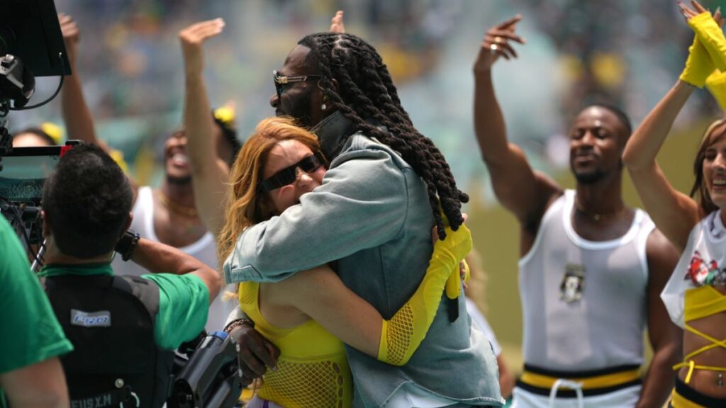 Shakira sonriendo y cantando con un balón de fútbol en el fondo