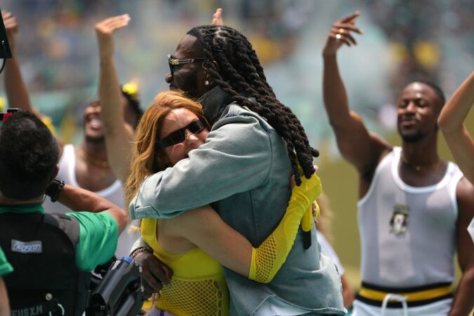 Shakira sonriendo y cantando con un balón de fútbol en el fondo