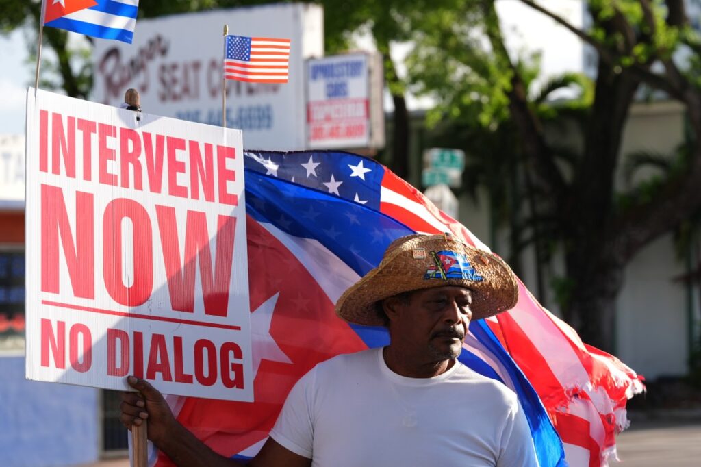 Imagen de una reunión diplomática entre Cuba y EE.UU. con banderas de ambos países al fondo