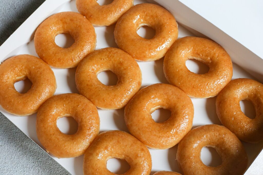 Una caja de donas Krispy Kreme con glaseado de colores y diseños de fútbol.
