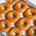 Una caja de donas Krispy Kreme con glaseado de colores y diseños de fútbol.