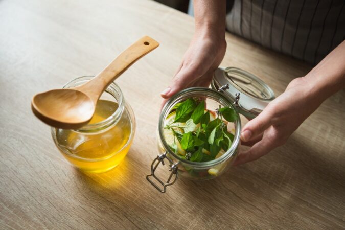 Una taza de té de toronjil caliente con hojas frescas y un limón al lado