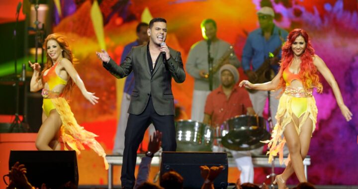Tito El Bambino sonriendo y hablando con un periodista en una entrevista